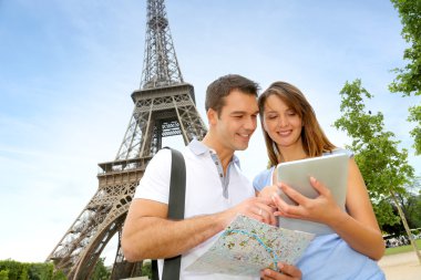 Tourists using electronic tablet in front of the Eiffel tower