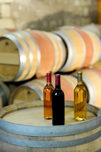 Closeup of bottles of wine set on barrel — Stock Photo, Image