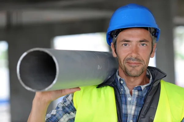 Bauarbeiter auf Baustelle hält Rohr — Stockfoto