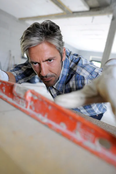 Hombre usando nivel dentro de casa en construcción — Foto de Stock