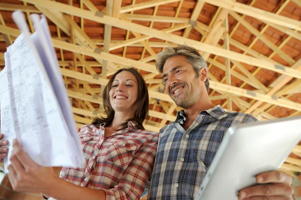 Couple joyeux debout à l'intérieur de la maison en construction — Photo