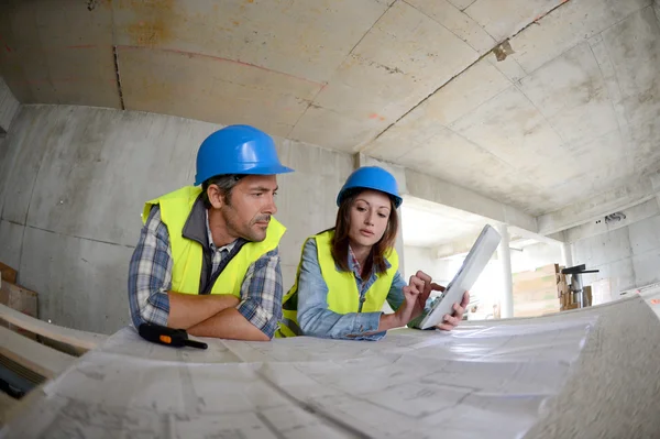 Equipe de trabalho verificando o modelo dentro da casa em construção — Fotografia de Stock