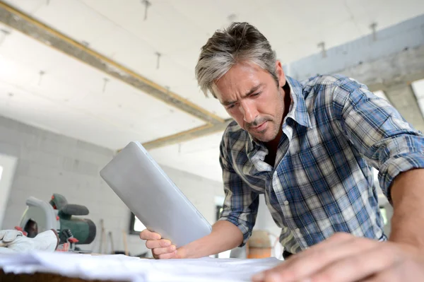 Ondernemer in huis in aanbouw controleren plan — Stockfoto