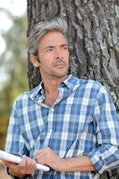 Middle-aged man leaning against tree — Stock Photo, Image