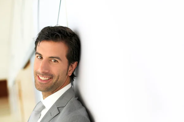 Geschäftsmann steht auf weißer Wand - Profilansicht — Stockfoto