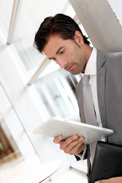 Uomo d'affari in piedi in sala con tablet elettronico — Foto Stock