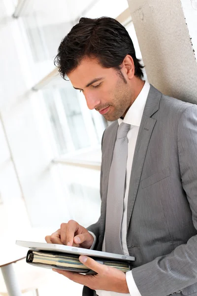 Businessman standing in hall with electronic tablet — Stock Photo, Image