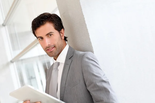 Businessman standing in hall with electronic tablet — Stock Photo, Image