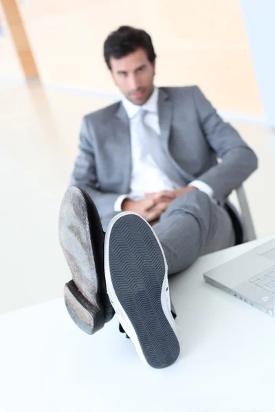 Üzletember pihentető wih lábak-on iskolapad — Stock Fotó