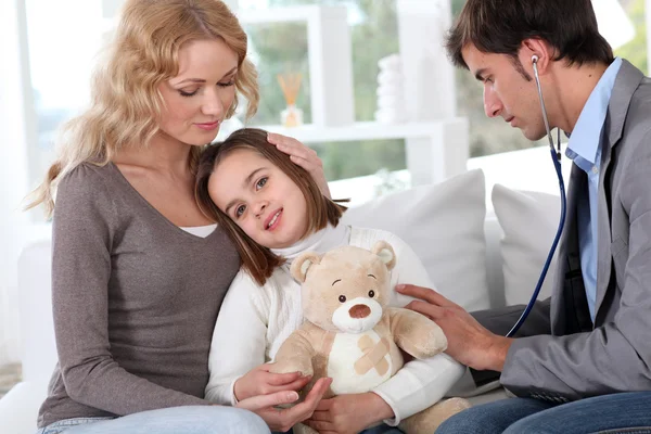 Enfermo niña sosteniendo osito de peluche mientras médico comprobar su — Foto de Stock