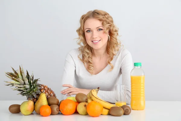 Meyve masada oturan sarışın bir kadın gülümsüyor — Stok fotoğraf