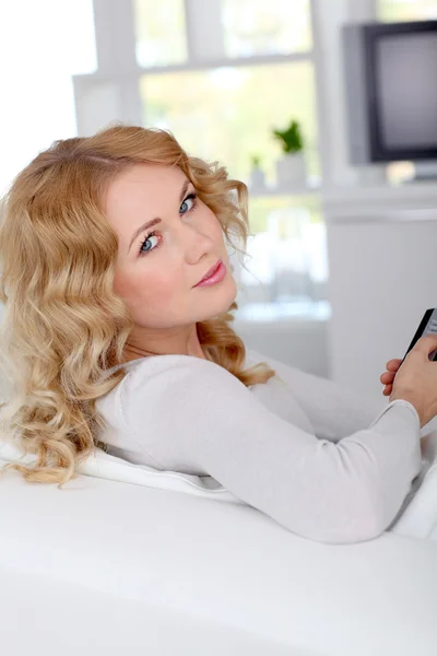 Krásná blonďatá žena sedí v pohovce u televize — Stock fotografie