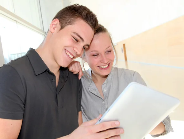 Amis dans le couloir scolaire en utilisant une tablette électronique — Photo