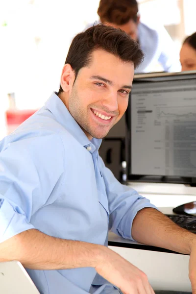 Comerciante sorrindo na frente do computador desktop — Fotografia de Stock