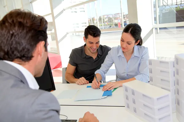 Casal em agência imobiliária que assina contrato de empréstimo imobiliário — Fotografia de Stock