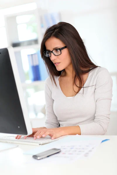 Beautiful office worker in front of desktop computer — Stock Photo, Image