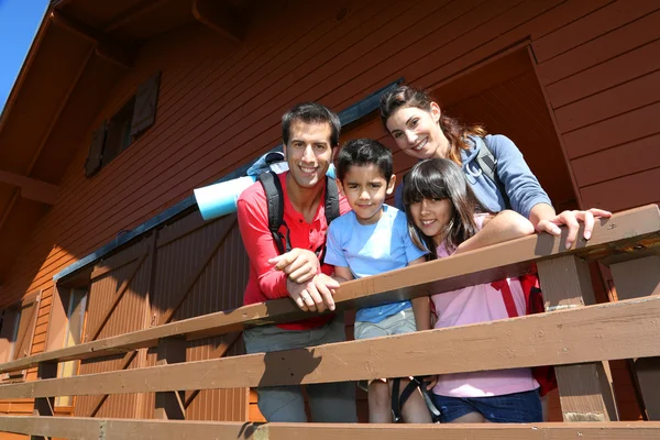 Retrato da família em pé na porta da frente da cabine de madeira — Fotografia de Stock