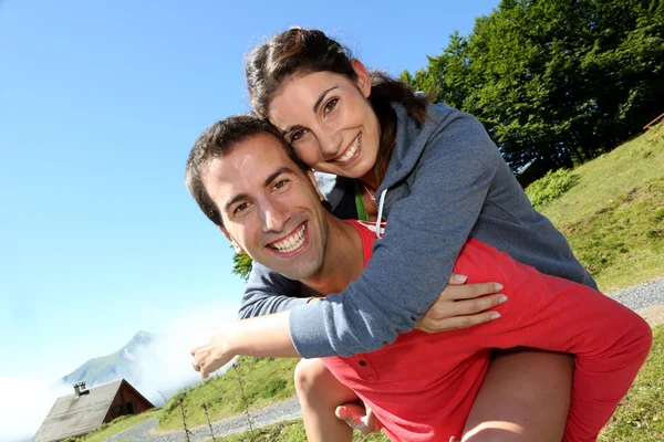 Mann gibt Freundin Huckepackfahrt an einem Trekkingtag — Stockfoto