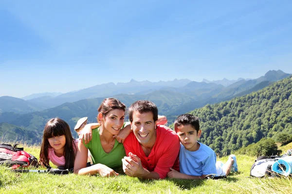 Portrait of happy family laying on the grass in mountain — Stock Photo, Image