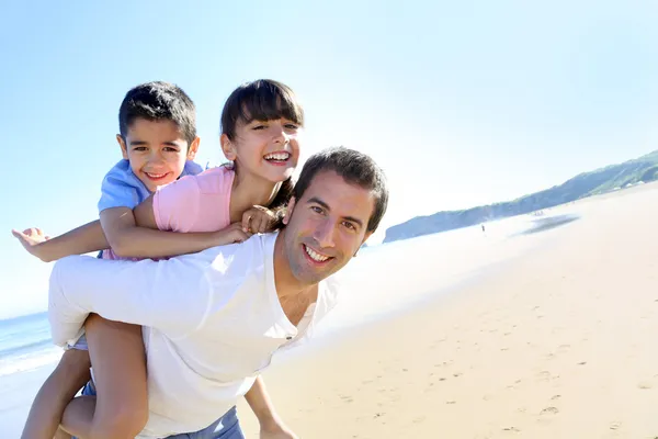 Papa trägt Kinder auf dem Rücken am Strand — Stockfoto