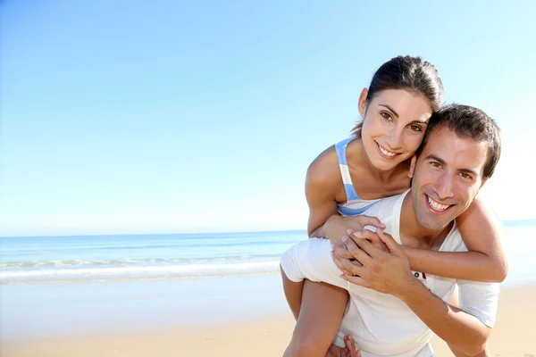 Hombre llevando novia en su espalda en la playa —  Fotos de Stock