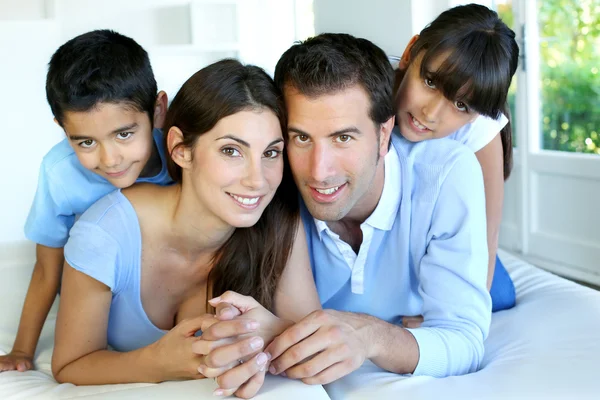 Retrato de família feliz deitado cama — Fotografia de Stock