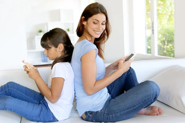 Mãe e filha usando telefone celular em casa — Fotografia de Stock