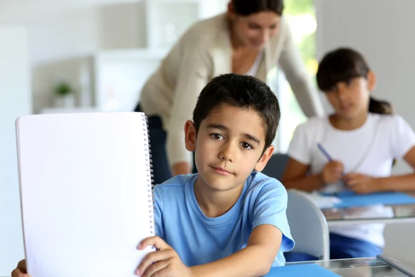 Porträt eines süßen kleinen Jungen, der sein Notizbuch in Richtung Kamera zeigt — Stockfoto