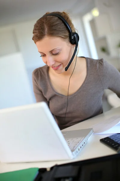 Giovane donna che lavora da casa con laptop e auricolare — Foto Stock