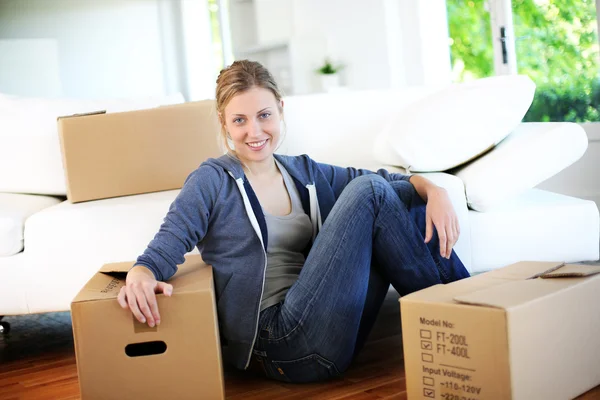 Young girl sitting by cardboards in new home — Stock Photo, Image