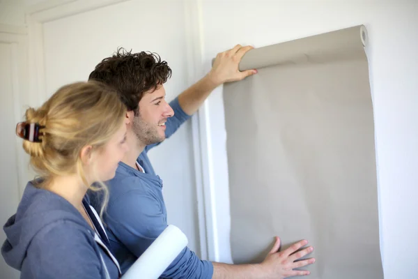 Pareja joven eligiendo el color de todo el papel en un nuevo hogar — Foto de Stock