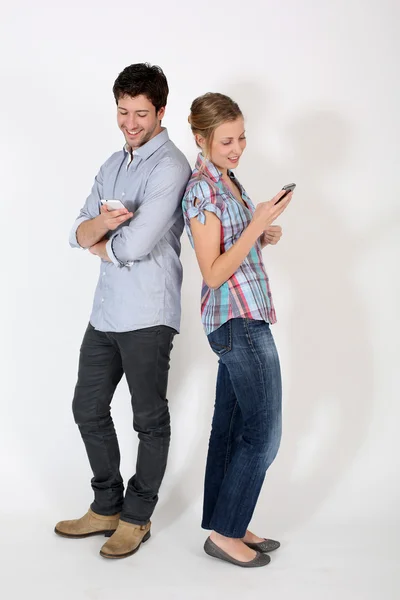 Casal jovem de pé de volta para trás com celular — Fotografia de Stock