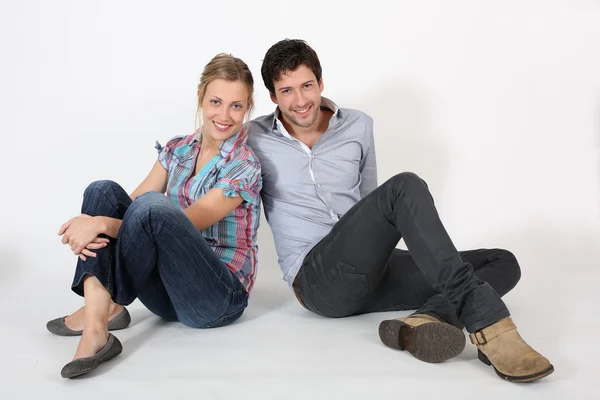 Young couple of students sitting on the floor — Stock Photo, Image