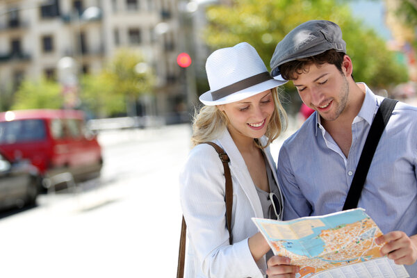 Trendy young couple in town with touristic map