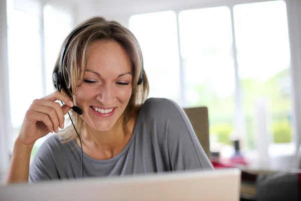 Porträtt av kvinna med headset framför laptop — Stockfoto