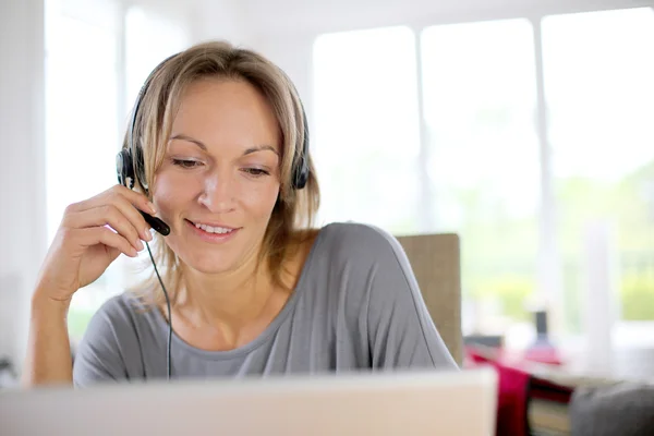 Ritratto di donna con auricolare davanti al computer portatile — Foto Stock