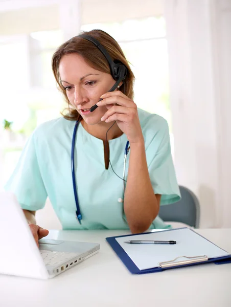 Verpleegster in de voorkant van de laptop met headset — Stockfoto