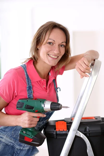 Woman standing on scale with electric drill — Stock Photo, Image