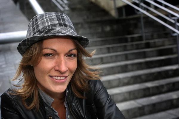 Portret van vrouw met hoed en lederen jas in de stad — Stockfoto