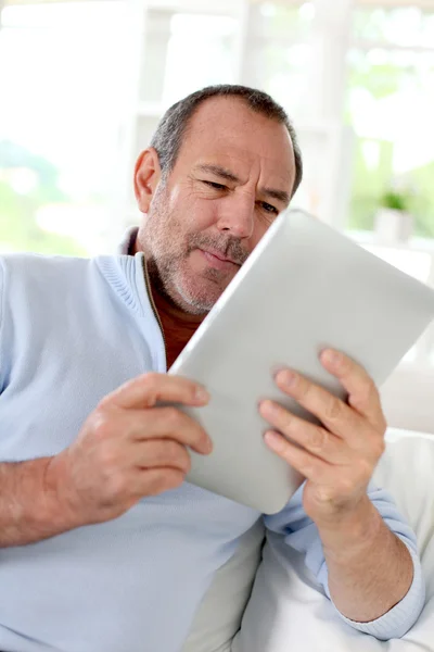 Старший чоловік вдома використовує електронний планшет — стокове фото