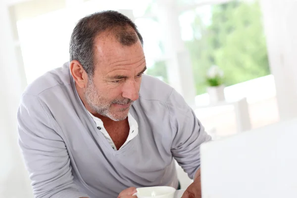 Homme âgé connecté sur Internet avec ordinateur portable à la maison — Photo