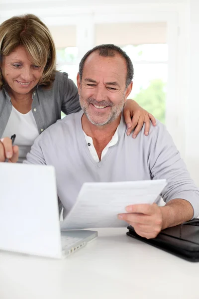 Couple âgé à la maison déclarant un revenu sur Internet — Photo