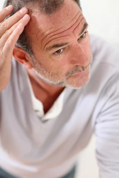 Senior man looking at his hair in mirror — Stock Photo, Image