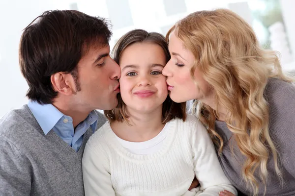 父母亲吻他们的女儿的肖像 免版税图库图片