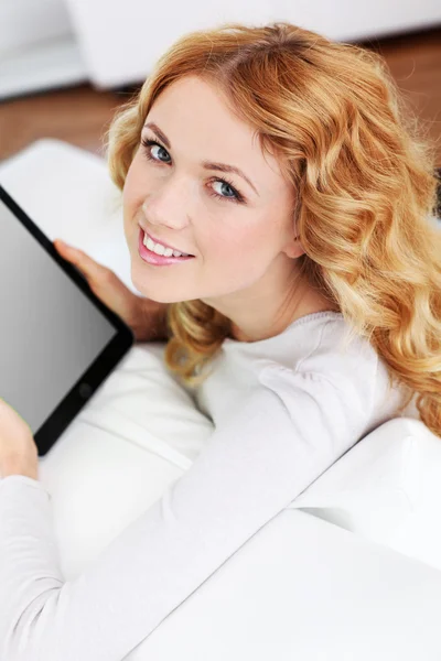 Mulher loira relaxando no sofá usando tablet eletrônico Imagem De Stock
