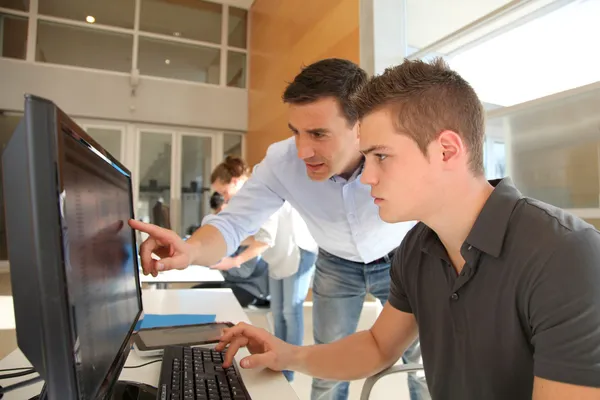 Lärare och student arbetar på dator Stockbild