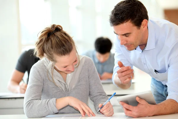 Teacher with student girl writing assignment Stock Image