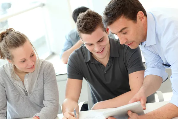 Teacher helping students with assignment Stock Photo
