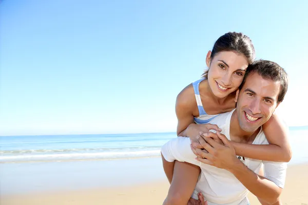 Man carrying girlfriend on his back at the beach Stock Image