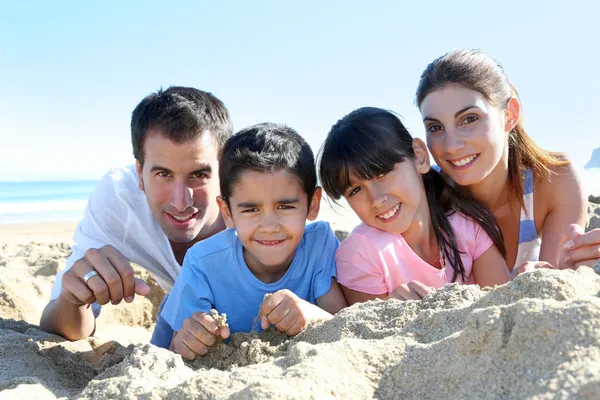 Família de quatro que põe em uma praia arenosa Imagem De Stock